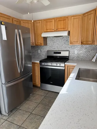 a kitchen with stainless steel appliances granite countertop a refrigerator a stove and a sink