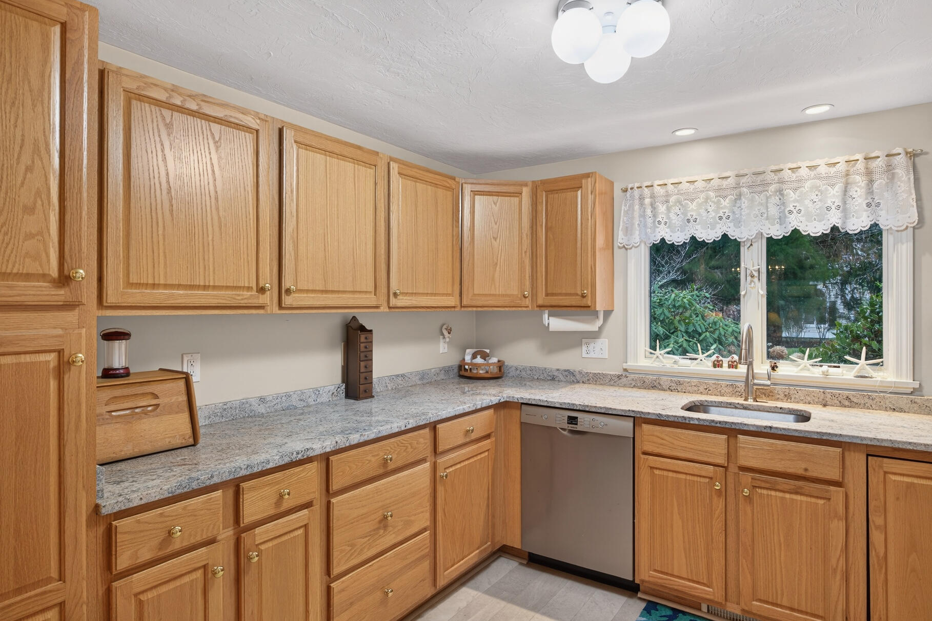 18 Windward Street, Unit 18 Mashpee, MA 02649 - Photo 14 of 34 a kitchen with granite countertop a sink window and cabinets