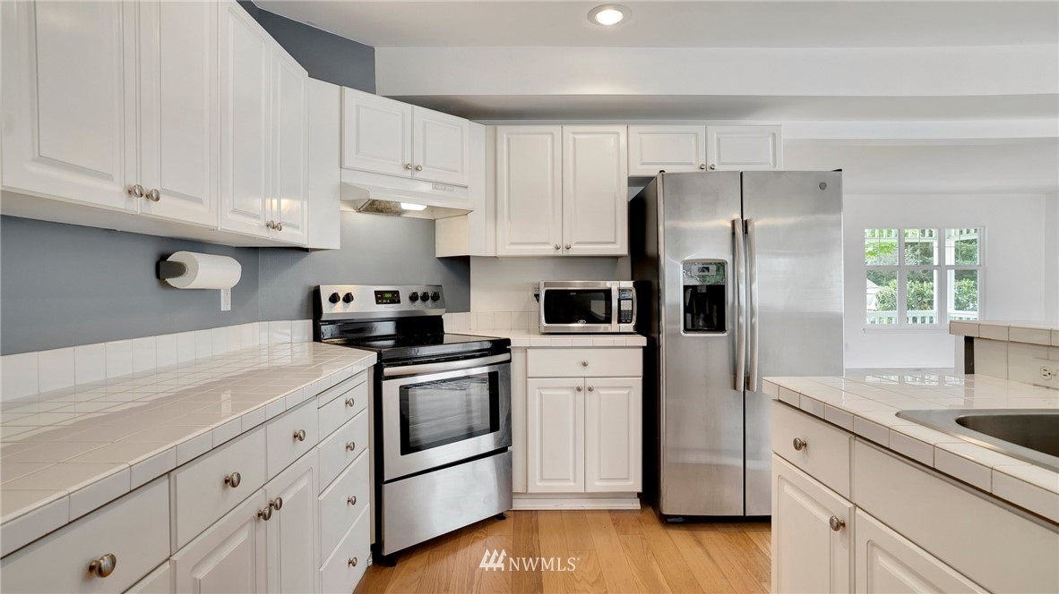 511 Redmond Place Northeast Renton, WA 98056 - Photo 13 of 31 a kitchen with white cabinets and stainless steel appliances