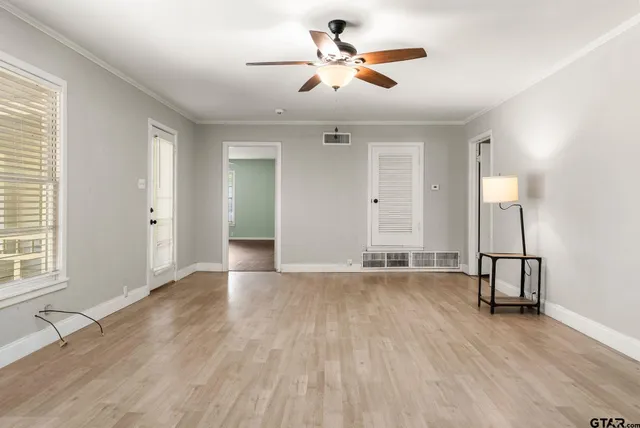 an empty room with wooden floor and windows