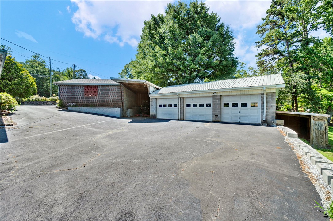 7876 Highway 11 Walhalla, SC 29691 - Photo 9 of 35 A spacious asphalt driveway leads to a triple garage and carport, framed by mature trees.