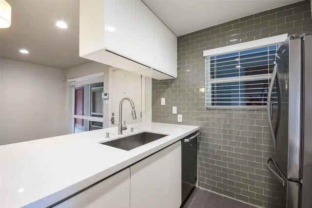 a kitchen with stainless steel appliances a sink a stove a refrigerator and cabinets