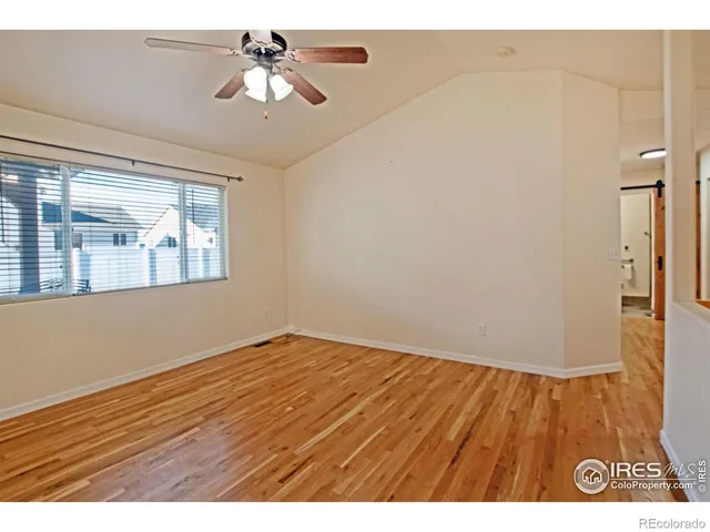 a view of an empty room with window and wooden floor