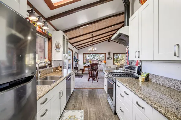 a kitchen with granite countertop lots of counter top space a sink and stainless steel appliances