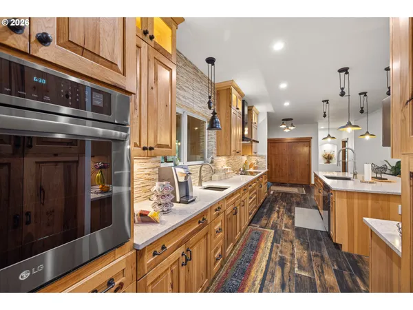 a open kitchen with stainless steel appliances kitchen island granite countertop a large kitchen island a stove a refrigerator a sink and dishwasher with wooden floor