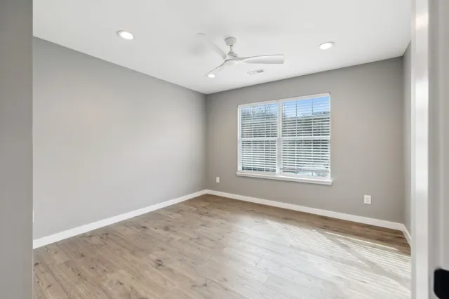 an empty room with wooden floor and windows
