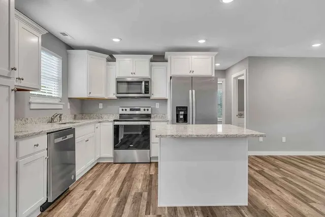 a kitchen with stainless steel appliances granite countertop a stove top oven a sink and a refrigerator