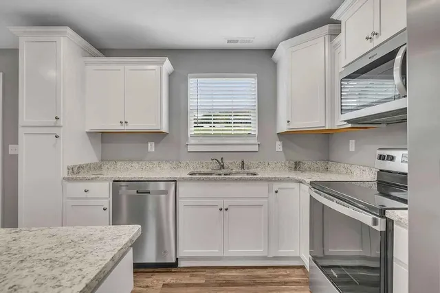 a kitchen with granite countertop cabinets stainless steel appliances and a sink