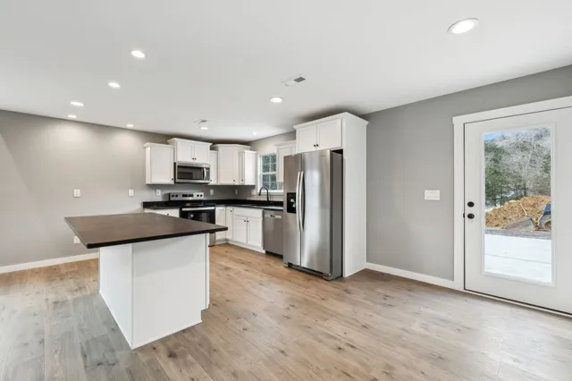 a kitchen with stainless steel appliances kitchen island wooden cabinets and refrigerator