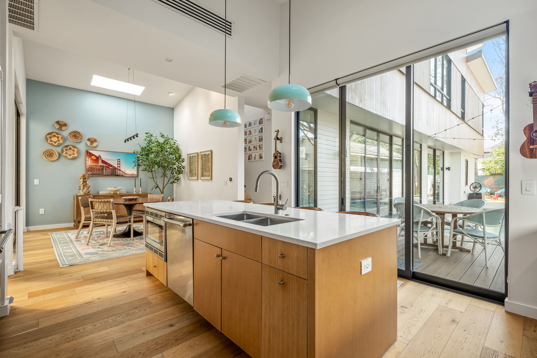 1811 Collier Street Austin, TX 78704 - Photo 7 of 40 Kitchen featuring a skylight, a kitchen island with sink, light wood-style flooring, hanging light fixtures, and a high ceiling