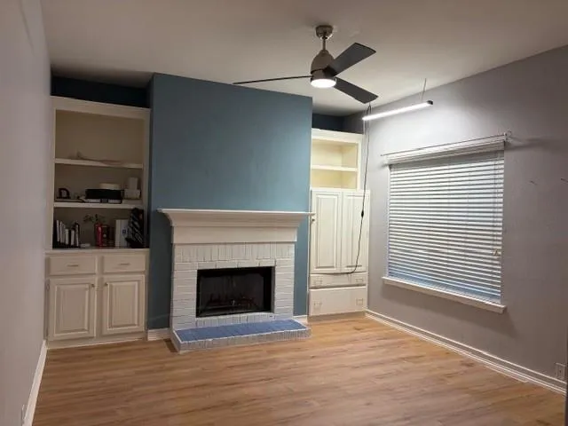 a view of a livingroom with wooden floor a fireplace and windows