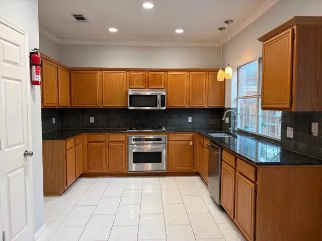a kitchen with stainless steel appliances granite countertop a stove a sink and a microwave