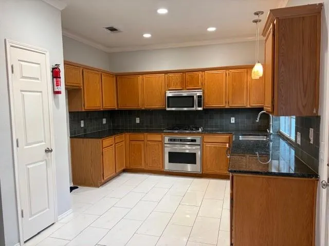 a kitchen with stainless steel appliances a stove a sink a microwave a refrigerator and cabinets