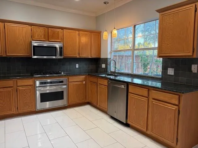 a kitchen with stainless steel appliances granite countertop a stove a sink and a microwave