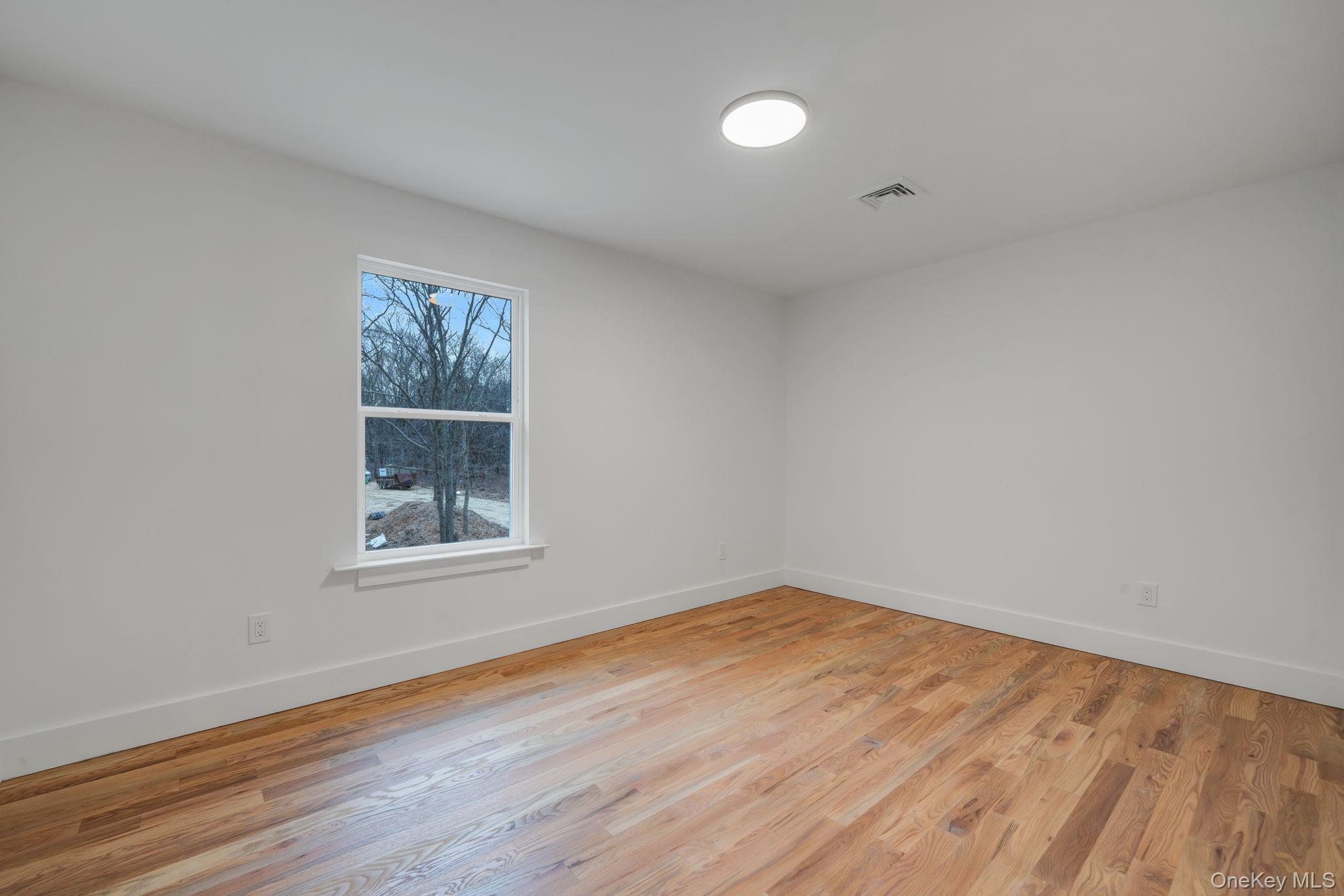 63 B Blydenburgh Road Centereach, NY 11720 - Photo 24 of 38 an empty room with wooden floor and windows