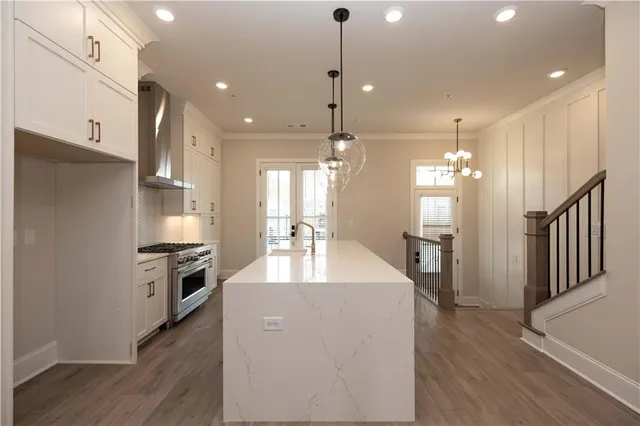a large kitchen with a center island wooden floor and stainless steel appliances
