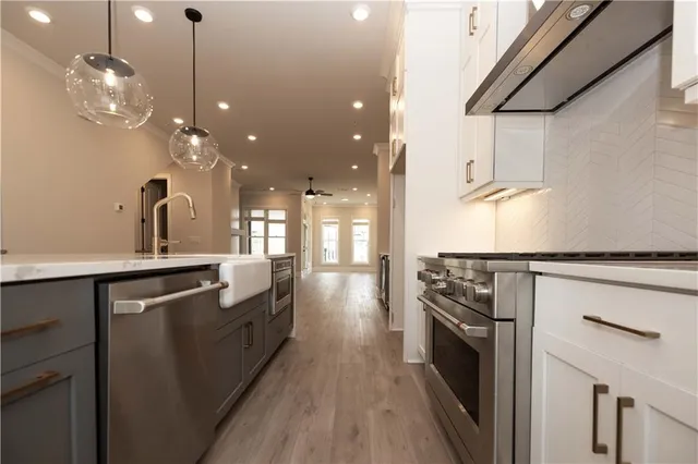 a kitchen with stainless steel appliances granite countertop a sink a stove and a wooden floors