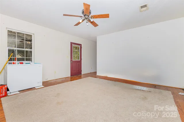 an empty room with ceiling fan and window