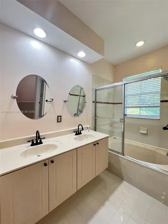 a bathroom with a double vanity sink mirror and bathtub