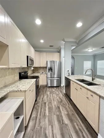 a large kitchen with stainless steel appliances kitchen island a sink dishwasher a stove and white cabinets with wooden floor