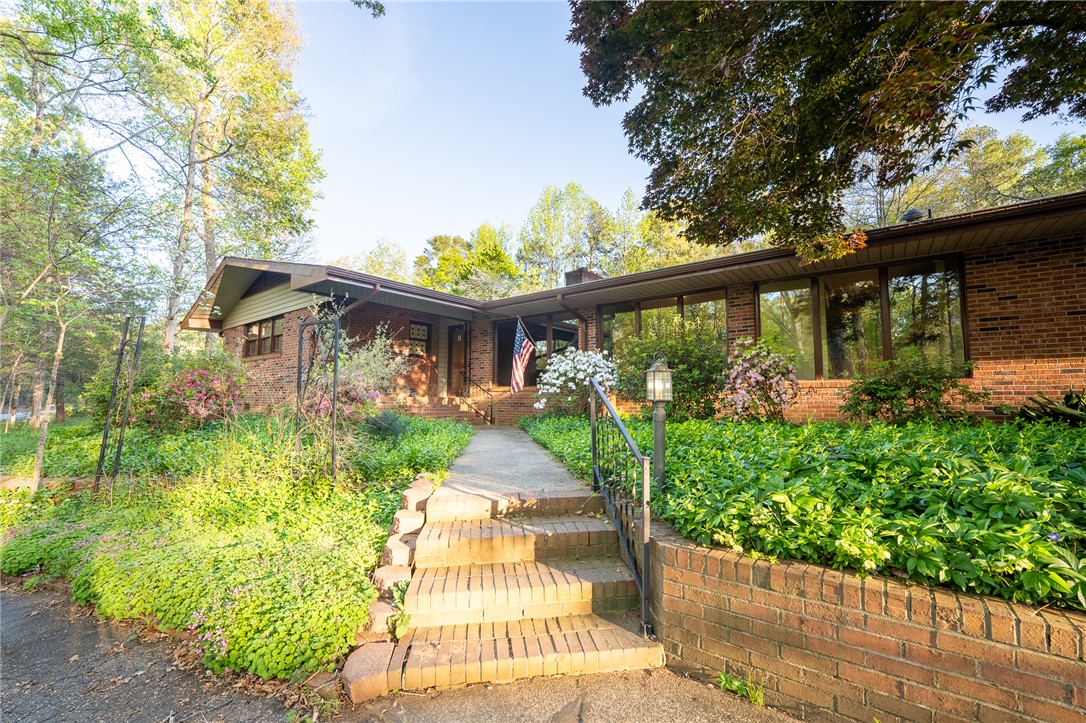 This charming residence features brick construction, inviting steps, and mature landscaping.