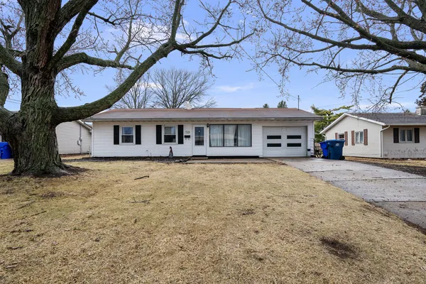 a view of house with a big yard and large tree