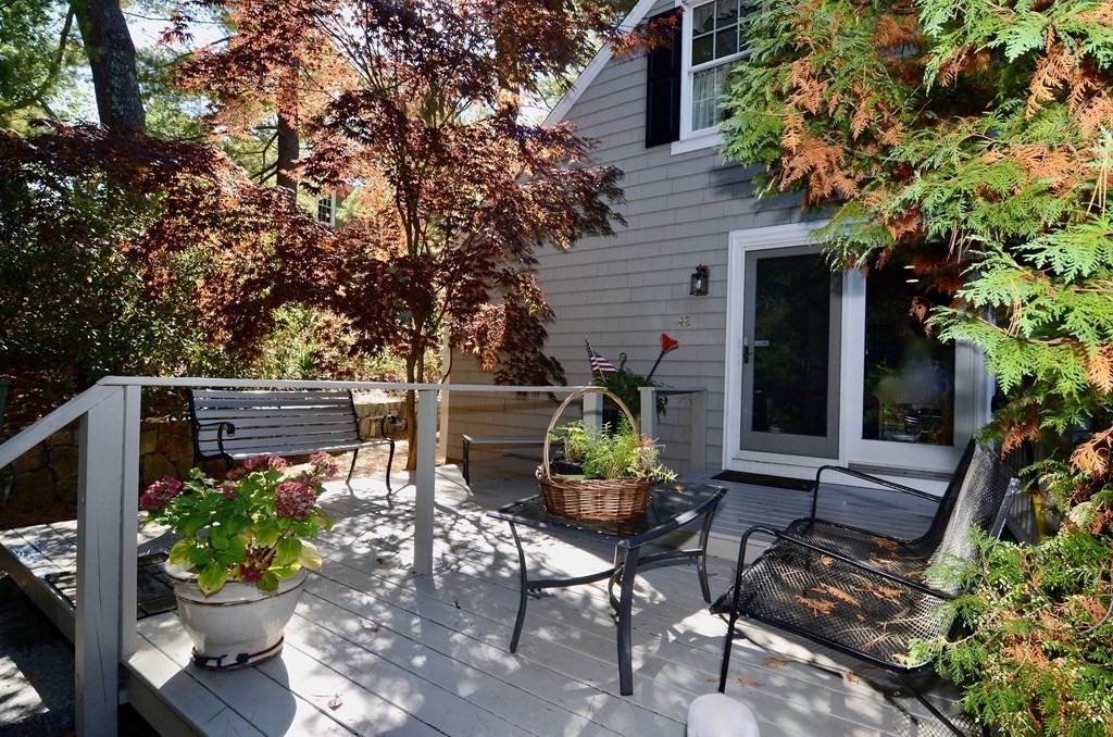 a backyard of a house with table and chairs potted plants and a large tree