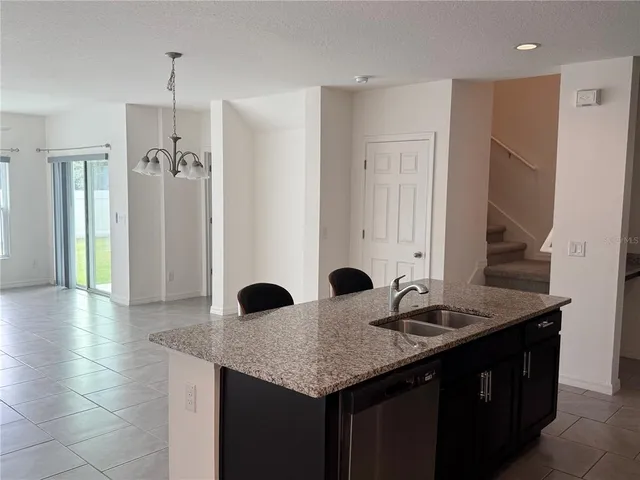 a kitchen with granite countertop a sink and a refrigerator