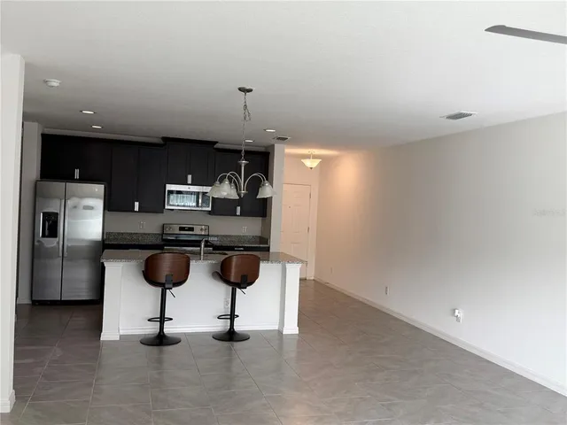 a kitchen with a refrigerator and chairs