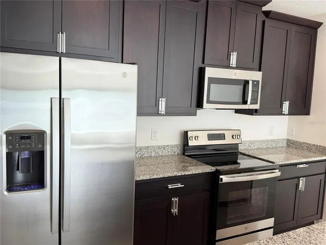 a kitchen with granite countertop cabinets stainless steel appliances and a counter space