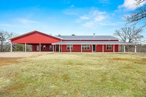 a front view of house with yard and trees in the background
