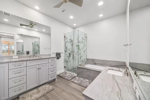 a spacious bathroom with a granite countertop sink a toilet a mirror and shower