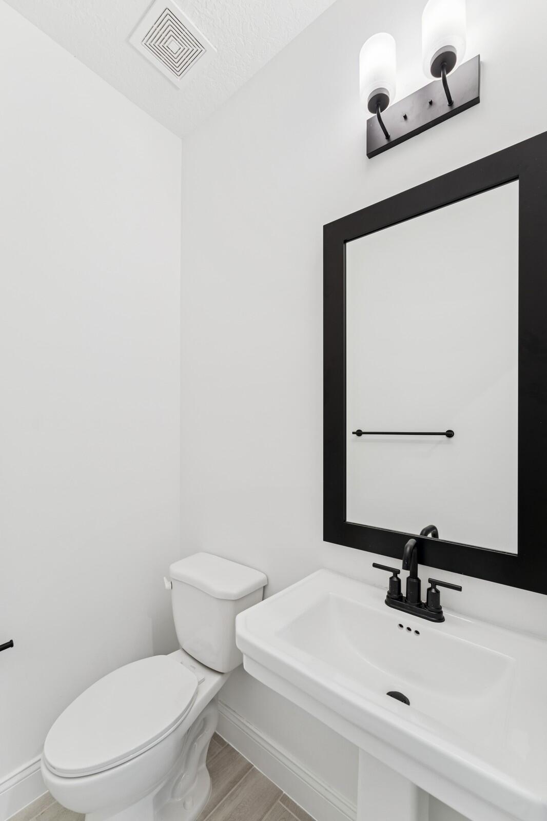 188 Southeast Birch Terrace, Unit 313 Stuart, FL 34997 - Photo 4 of 30 a bathroom with a sink mirror and toilet