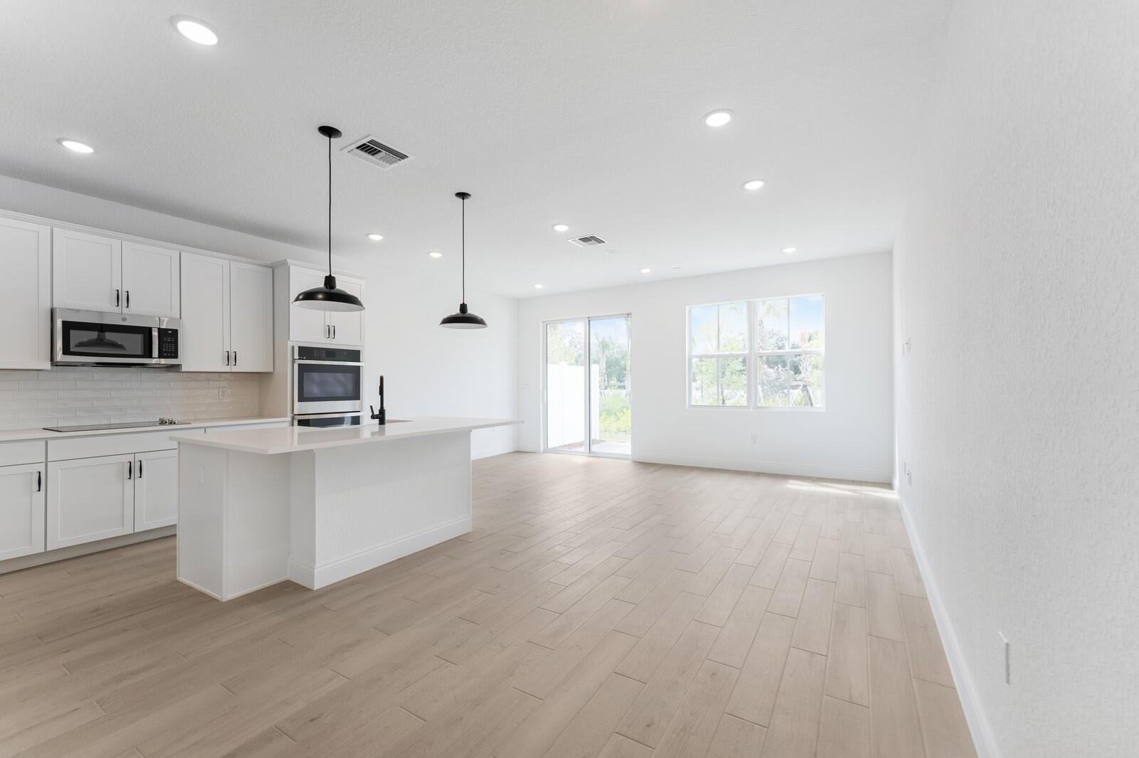 188 Southeast Birch Terrace, Unit 313 Stuart, FL 34997 - Photo 5 of 30 a large kitchen with white cabinets a sink dishwasher a stove and a refrigerator