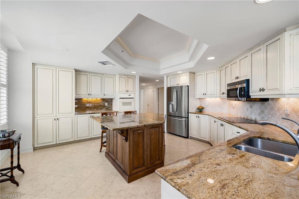 435 Dockside Drive, Unit A804 Naples, FL 34110 - Photo 16 of 50 Kitchen with light stone counters, stainless steel fridge with ice dispenser, backsplash, a raised ceiling, and recessed lighting