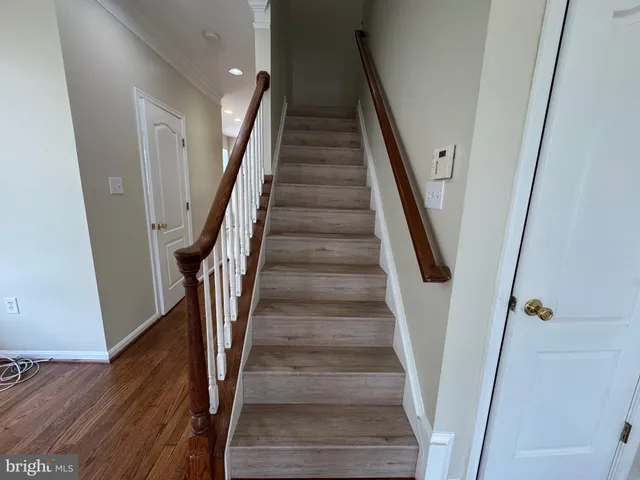 a view of staircase with wooden floor and white walls