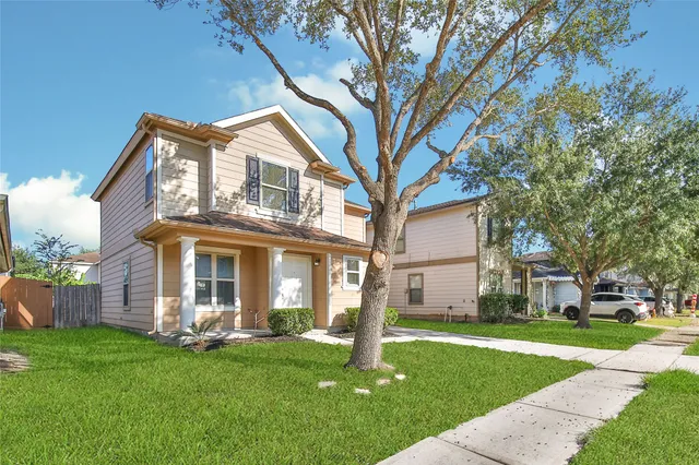 a view of a white house with a big yard plants and large trees