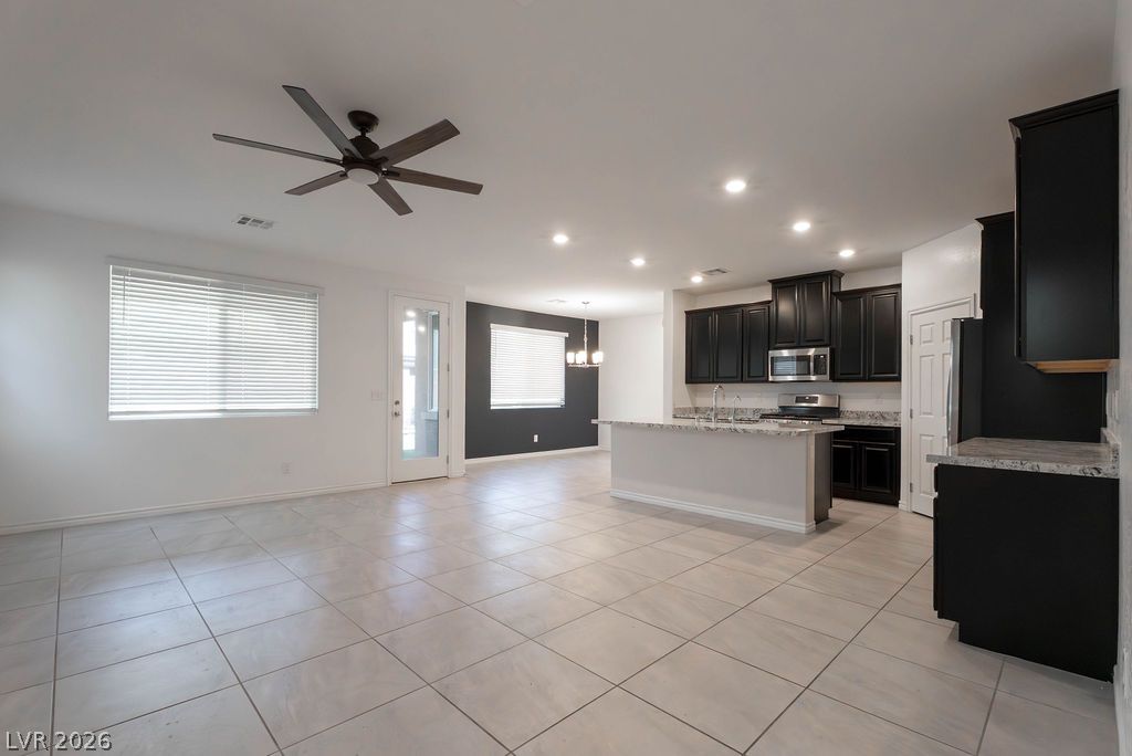 7126 Calvert Cliffs Street North Las Vegas, NV 89084 - Photo 3 of 44 An open-concept living area boasts a modern kitchen with dark cabinetry and a central island.