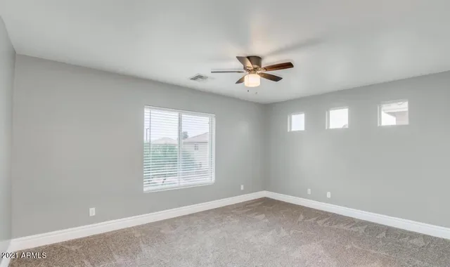 an empty room with a window and a ceiling fan
