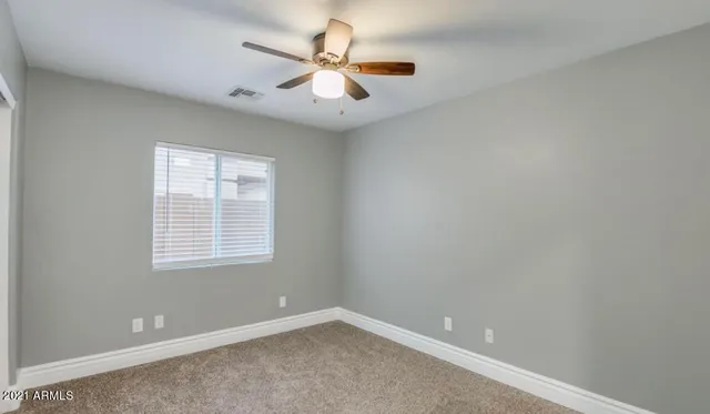 an empty room with a window and a fan
