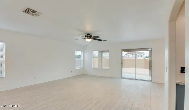 an empty room with chandelier fan and windows