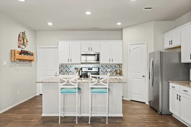 a kitchen with stainless steel appliances granite countertop a white cabinets and a refrigerator