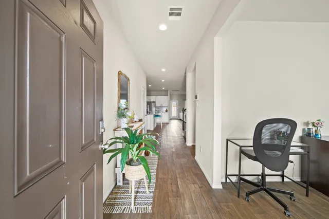 a view of a hallway with wooden floor and a potted plant