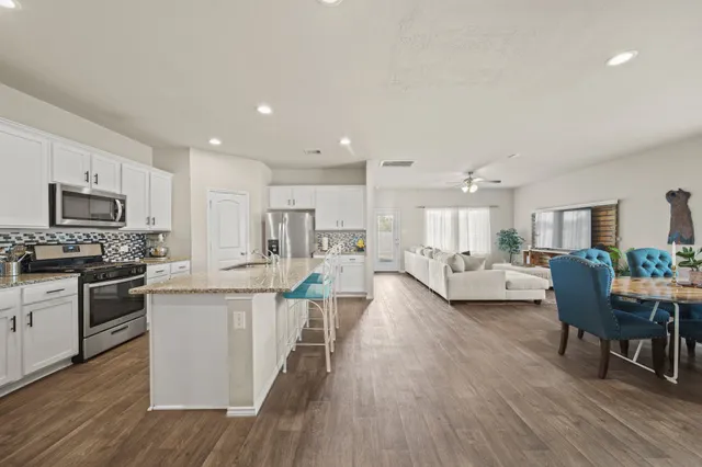 a living room with stainless steel appliances kitchen island granite countertop wooden floor a dining table and chairs
