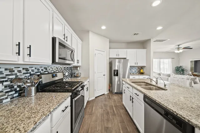 a kitchen with stainless steel appliances granite countertop a sink stove microwave and refrigerator