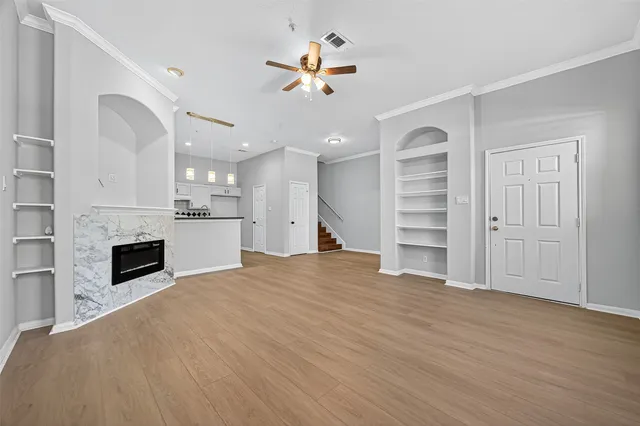 a view of an empty room with a window and wooden floor