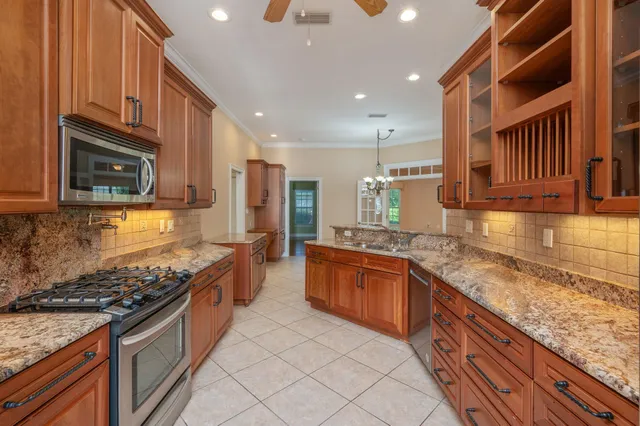 a large kitchen with stainless steel appliances granite countertop a stove a sink and a microwave