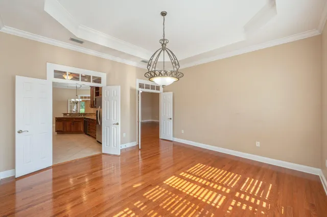 a view of a hallway with wooden floor and a chandelier