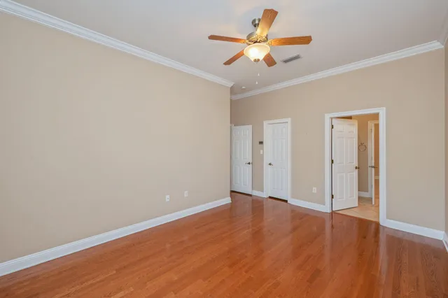 an empty room with wooden floor and a ceiling fan