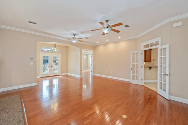a view of an empty room with wooden floor and a ceiling fan